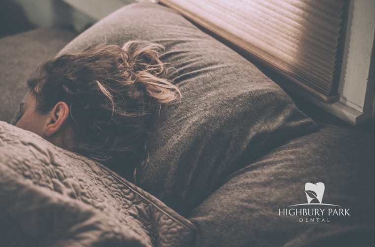 woman sleeps in bed with dark grey and earth toned sheets