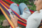 Women looking through her social media account on her phone while sitting in a hammock