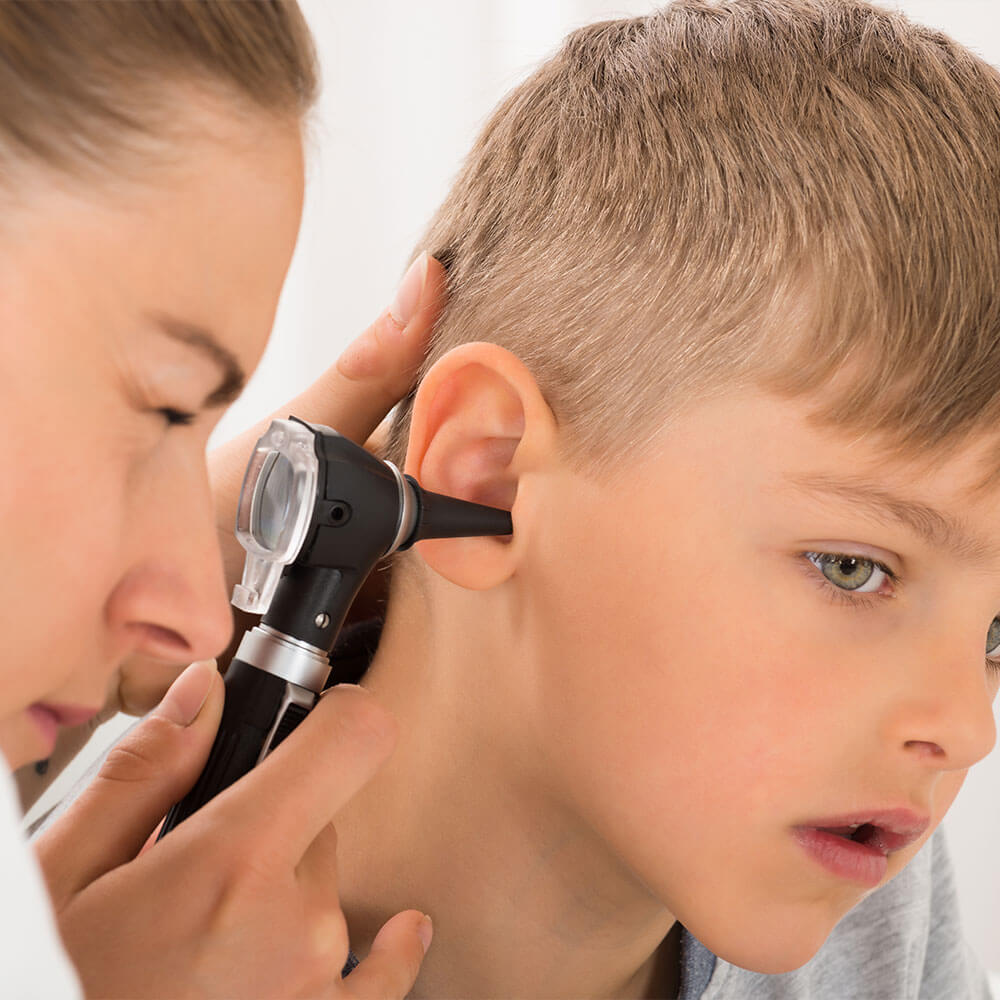 Nurse carefully checking a child’s ear for an ear flush treatment.