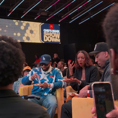 A group of judges eating off plates surrounded by a crowd with a McDonald's logo in the back