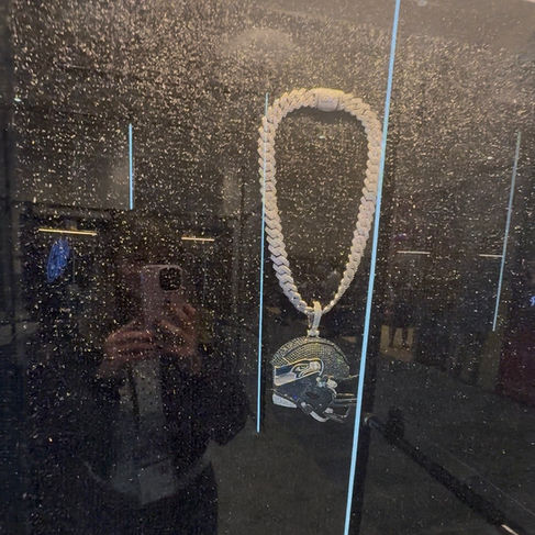 A diamond Seattle Seahawks helmet on a cuban link chain against a black foam mat