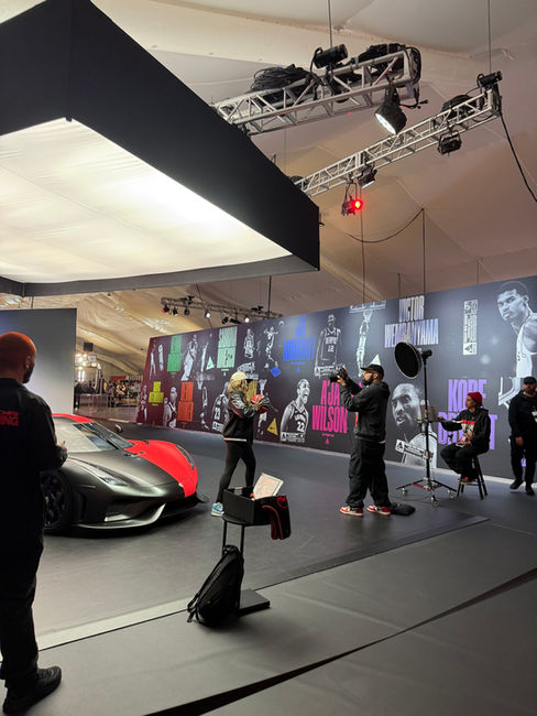 A woman posing for a photo in front of a red and black Koenigsegg Regera