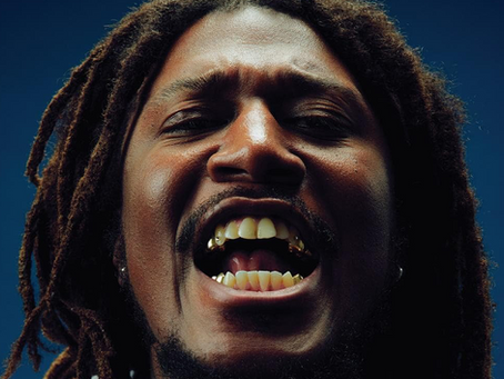 The cover art of AmirSaysNothing's "We Are Who We Say We Are" album featuring a photo of the rapper with his mouth open against a blue backdrop