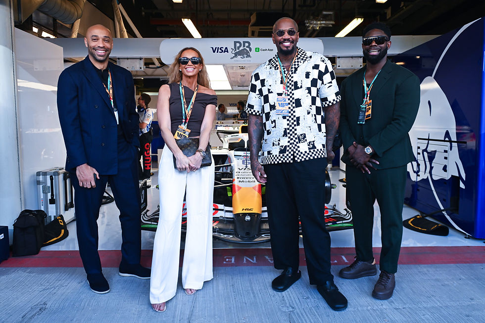 Thierry Henry, Kate Scott, Micah Richards and Malik Scott stand outside the Visa Cash App Racing Bulls garage in front of a Visa Cash App Racing Bulls F1 car