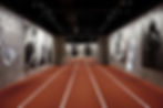 A hall of Emotions of the Athletic Body exhibition with a track on the floor and black and white photos on the walls