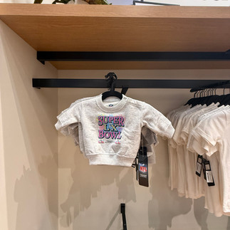 A gray baby sweatshirt that has the Super Bowl LX logo on it