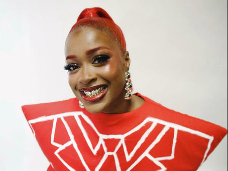 Tierra Whack smiles wearing a red structured top