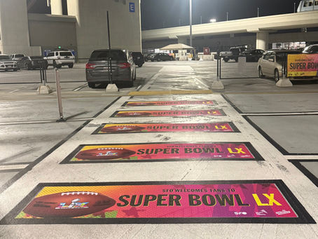 A walkway in a parking lot with pink banners that say "Super Bowl LX" on them