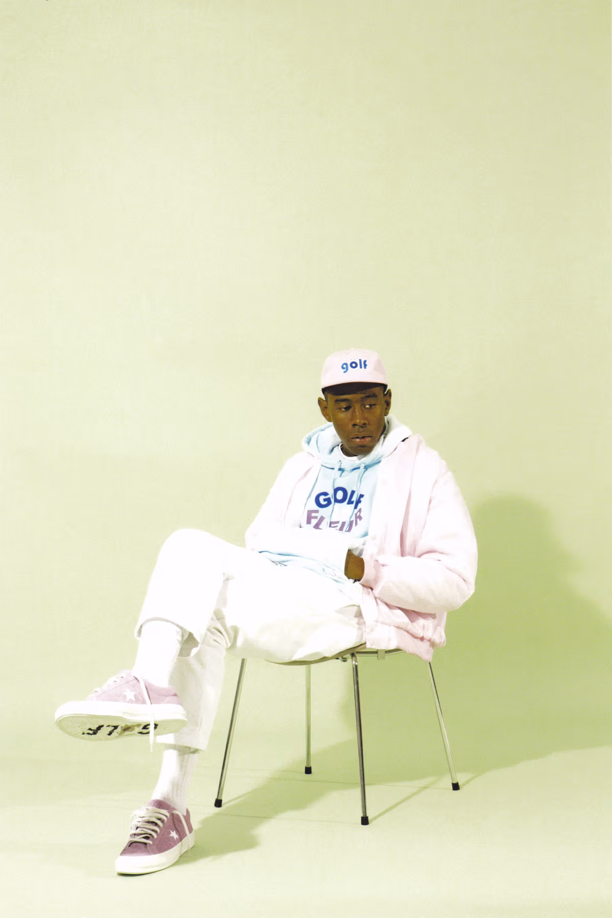 Tyler, The Creator sits in a chair modeling his Converse collab