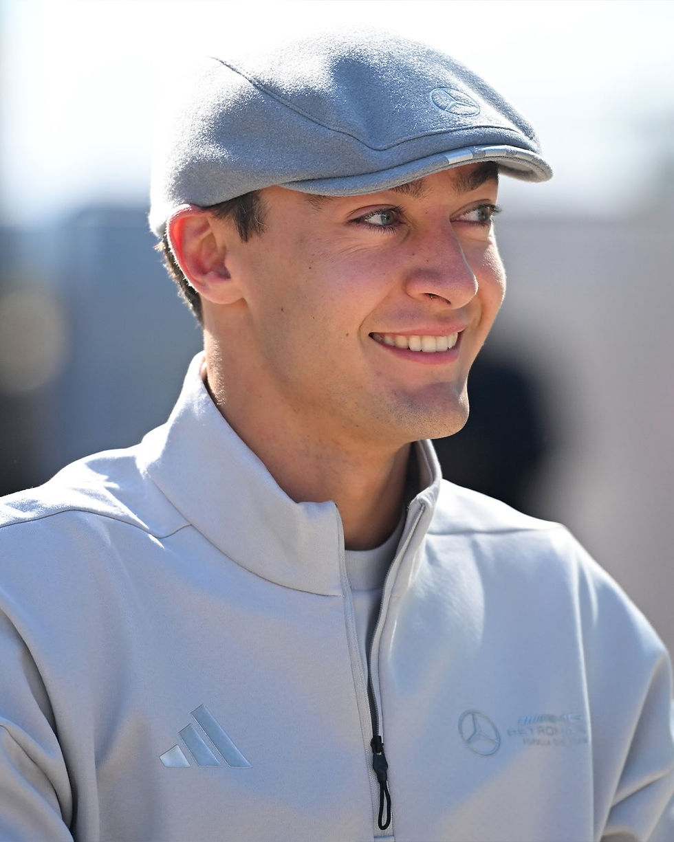 George Russell smiles while wearing a adidas x Mercedes newsboy cap at Silverstone
