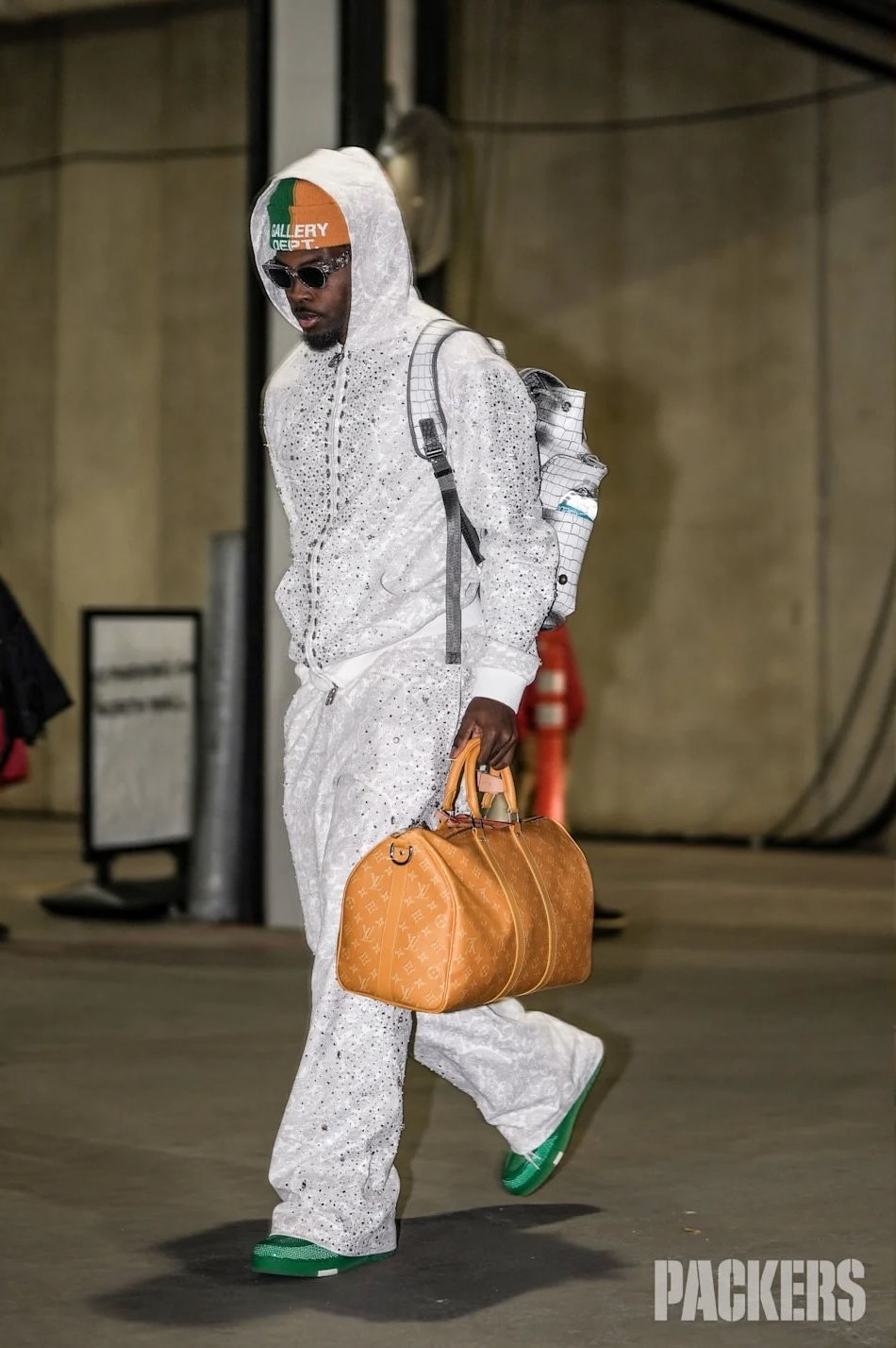 Jayden Reed walking in a parking garage wearing a white patterned sweatsuit