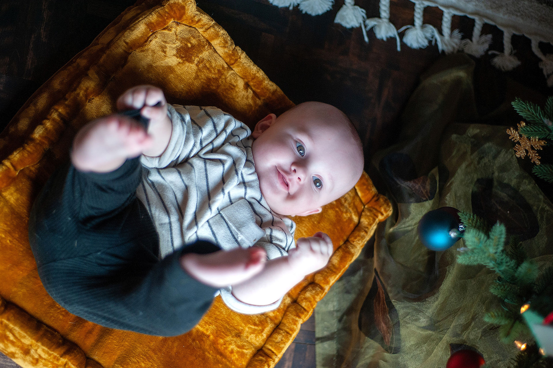 Baby lyging his back under a Christmas tree