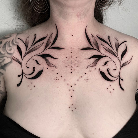 Tatuaggio ornamentale sul petto di Noemi con rami e puntinato