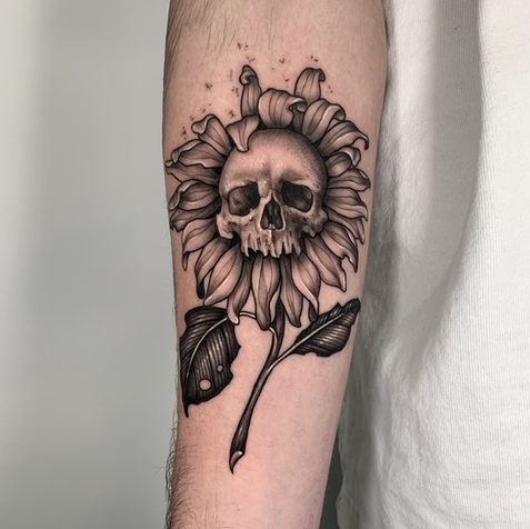 Tatuaggio di girasole con teschio al centro sul braccio