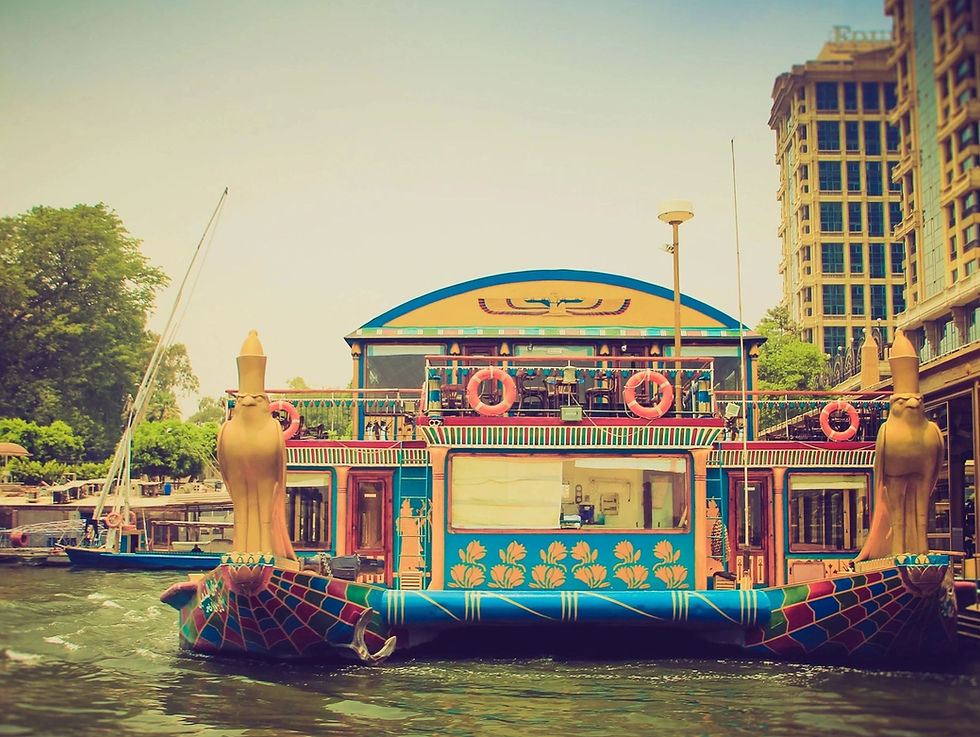 Wide angle view of a Nile cruise boat sailing at sunset with city lights in the background