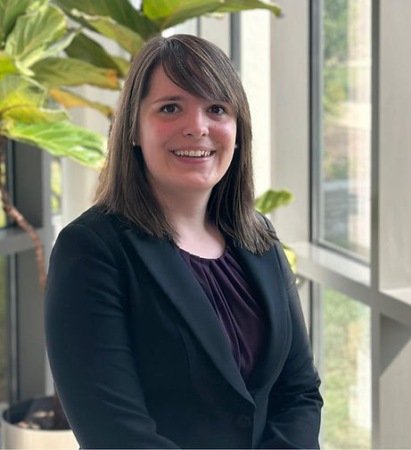 Callie Martindale, a woman with brunette hair, a purple tank and a black blazer, smiles warmly in front of a window frame.