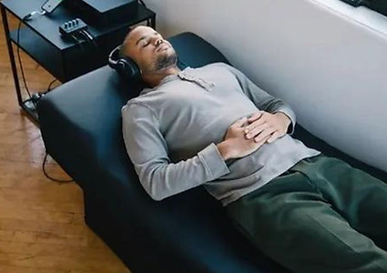 A man lying on a VAT table while listening to music with headphones.
