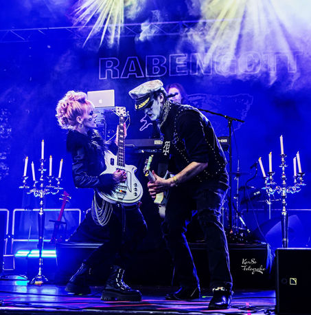 Foto eines Auftritts der Band Rabengott. Dennis und Denise schauen sich beim Gitarrespielen an während Julian am Stagepiano im Hintergrund spielt.