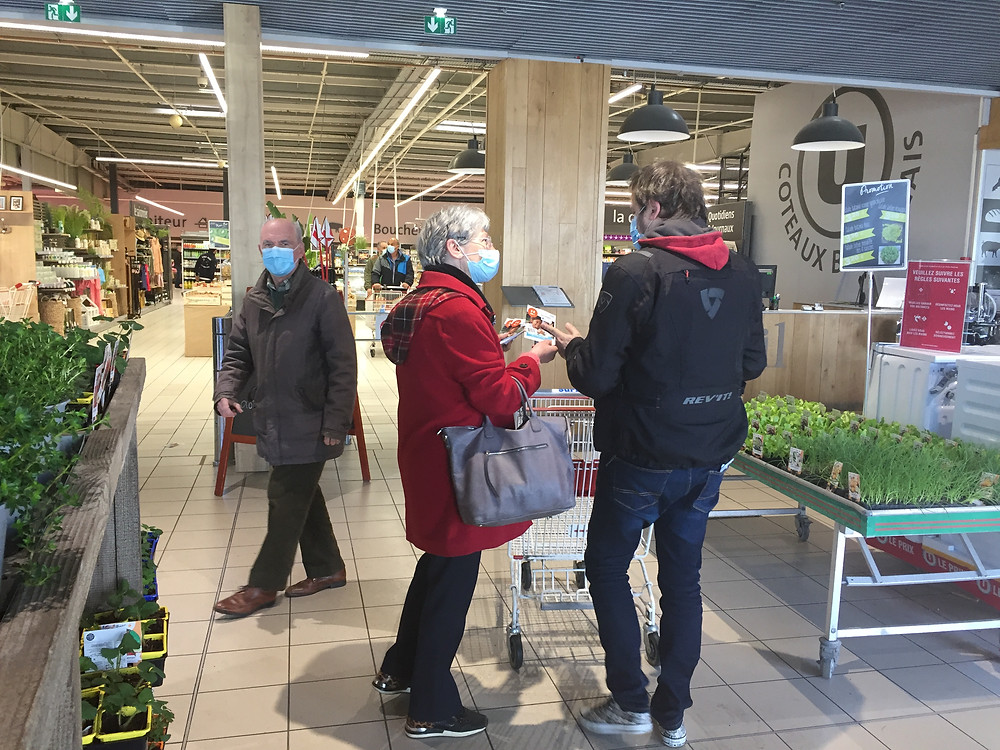 Une bénévole de PSE Aquitaine propose le flyer à l'entrée du magasin