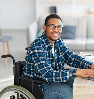 Man in wheelchair with glasses looking at camera and smiling