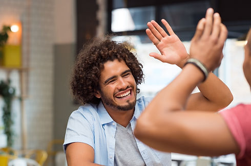 Man smiling and high fiving another male