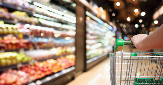 Blurred image of shopping cart with hand in grocery store aisle.