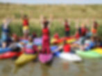 scouts in kayaks holding their arms up.