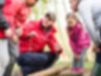 A scout leader showing cubs how to tie knots.