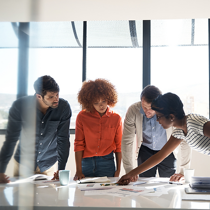 Four people looking at documents on table in a workplace environment.