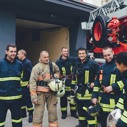 Firefighters standing around talking in front of a firetruck
