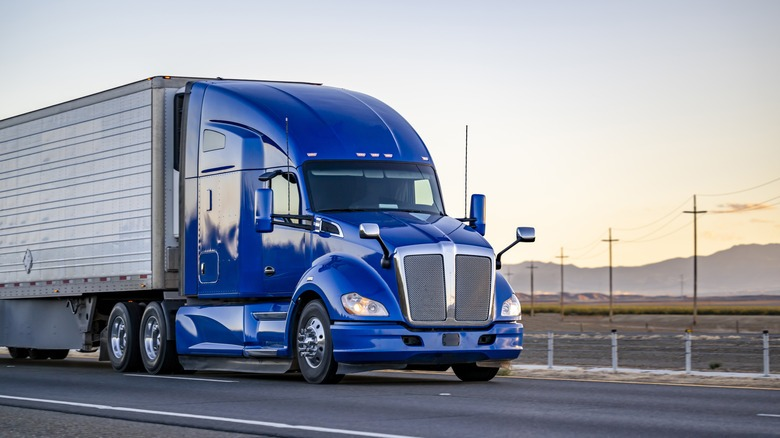 Blue semi-truck on highway, landscape view