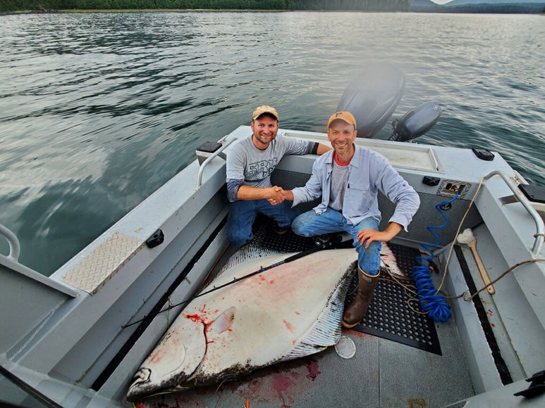 two people with halibut on board boat