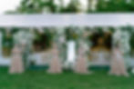 Four women in peach gowns play string instruments in front of a flower-adorned tent; elegant event setting with white and pastel florals. Lake Grada, Italy.