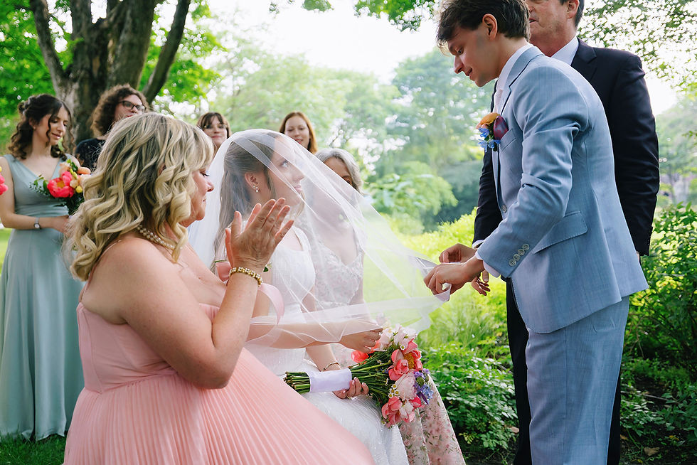 Veiling moment. Bride surrounded by family and friends during the bedeken before her Jewish wedding ceremony, with the groom coming to her