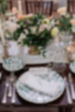 Elegant wedding table setting with green patterned plates and florals
