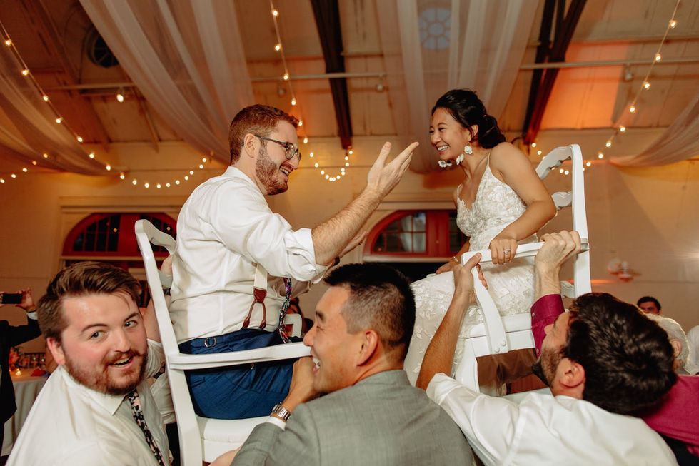 Wedding guests lifting the couple on chairs during a high-energy dance inside the Hunnewell Building.