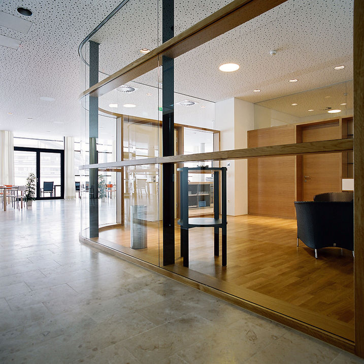 Seniorenresidenz Seefeld, vollverglaste Innenwand, Pfosten-Riegel-Konstruktion, links Steinboden, rechts Holzboden