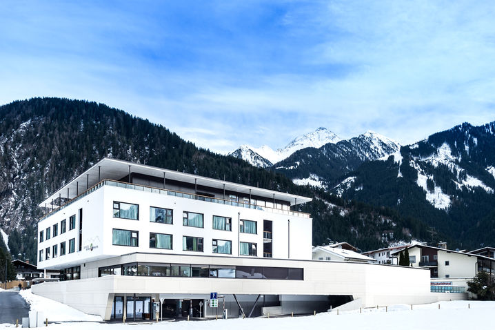 mit schnee bedeckter baukörper mit lochfassade obegeschoss und beton erdgeschoss