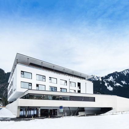 seitenansicht viergeschossiger baukörper in schneelandschaft eingebunden