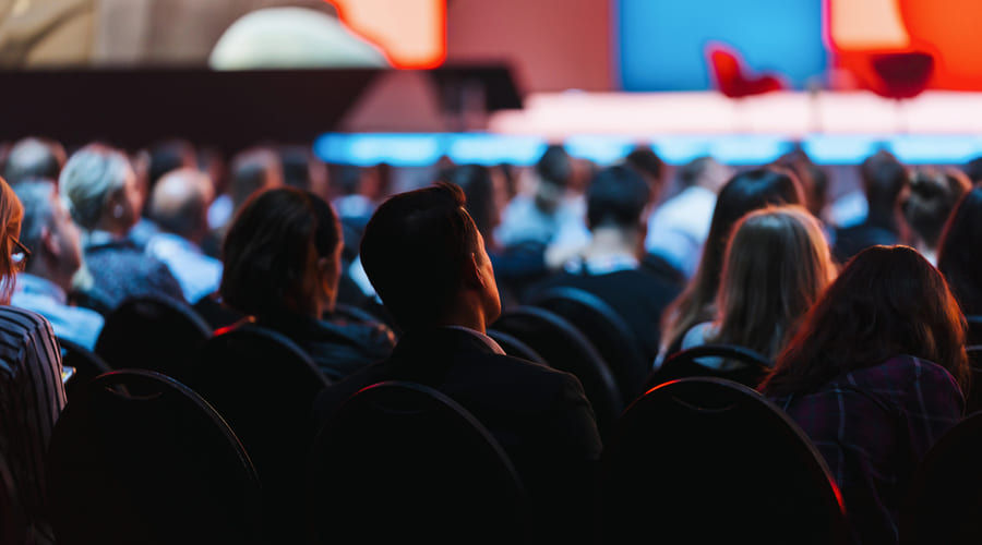 angled photo of a crowd seated looking at stage 
