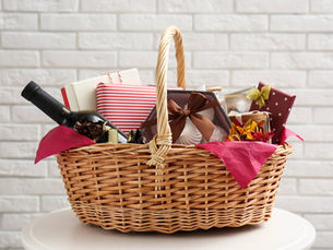 wicker basket filled with gift items like wine and chocolates