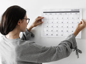 woman pinning calendar on wall