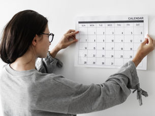 woman pinning calendar on wall