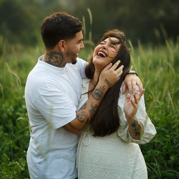 Casal sorrindo no meio do campo aberto