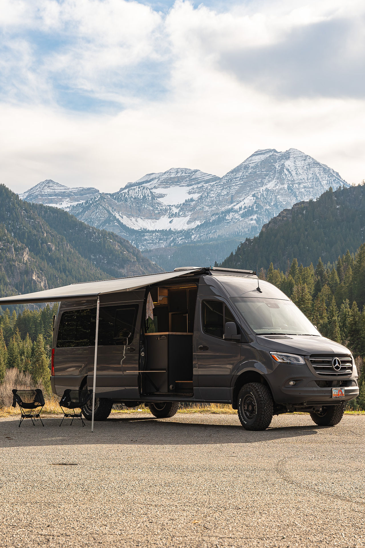 170" Mercedes Sprinter campervan with awning and seats set up in mountains of utah