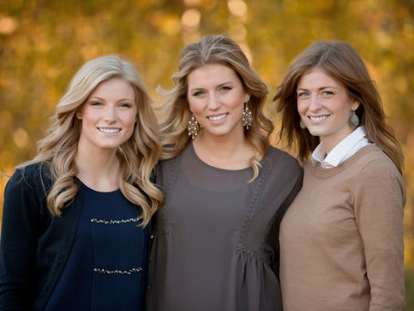 Three smiling young women standing together.