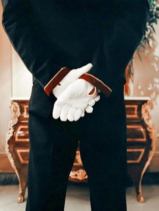 A white-gloved server holds a leather menu, a small mark of consistent standards.