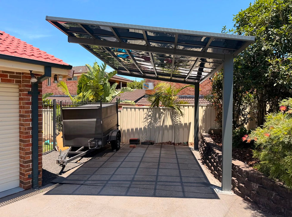 Modern metal carport over a paved driveway next to a house.