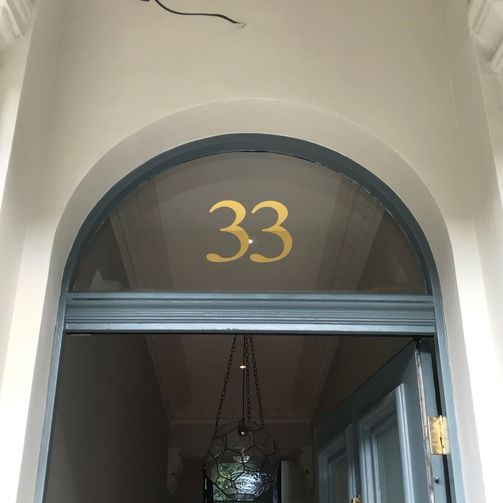 Golf leaf house number on arched transom above front door