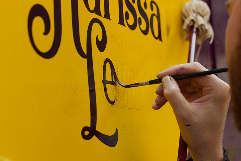 signwriter hand painting a sign for a food truck